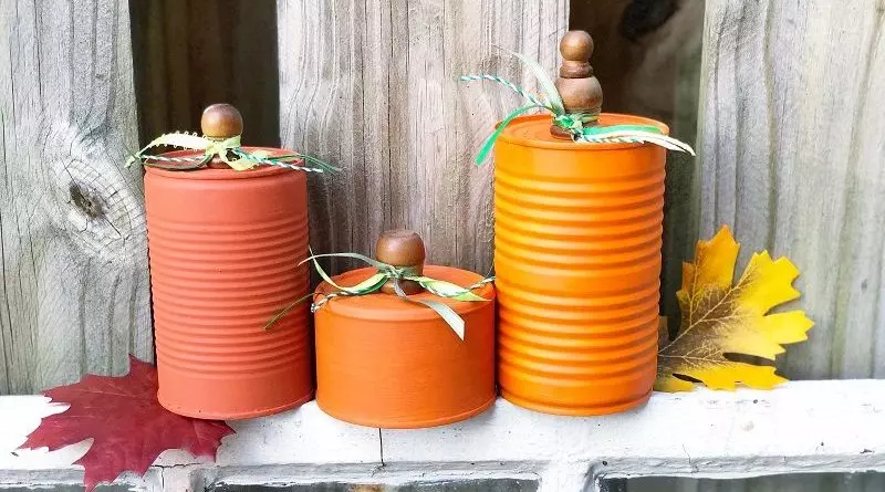 How to Recycle Tin Can Pumpkins for Autumn Creatively Beth Three orange cans sitting on a hay bale on a brick background #CreativelyBeth #recycledcrafts #fallcrafts #pumpkincrafts #autumncrafts